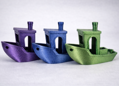 Three Benchy test boats printed in PETG-HS Metallic purple, blue and green