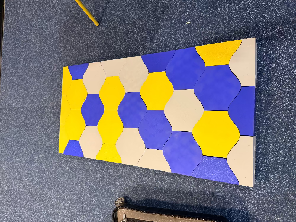 Close-up of blue, purple and yellow Matte PLA hexagon tiles on a panel