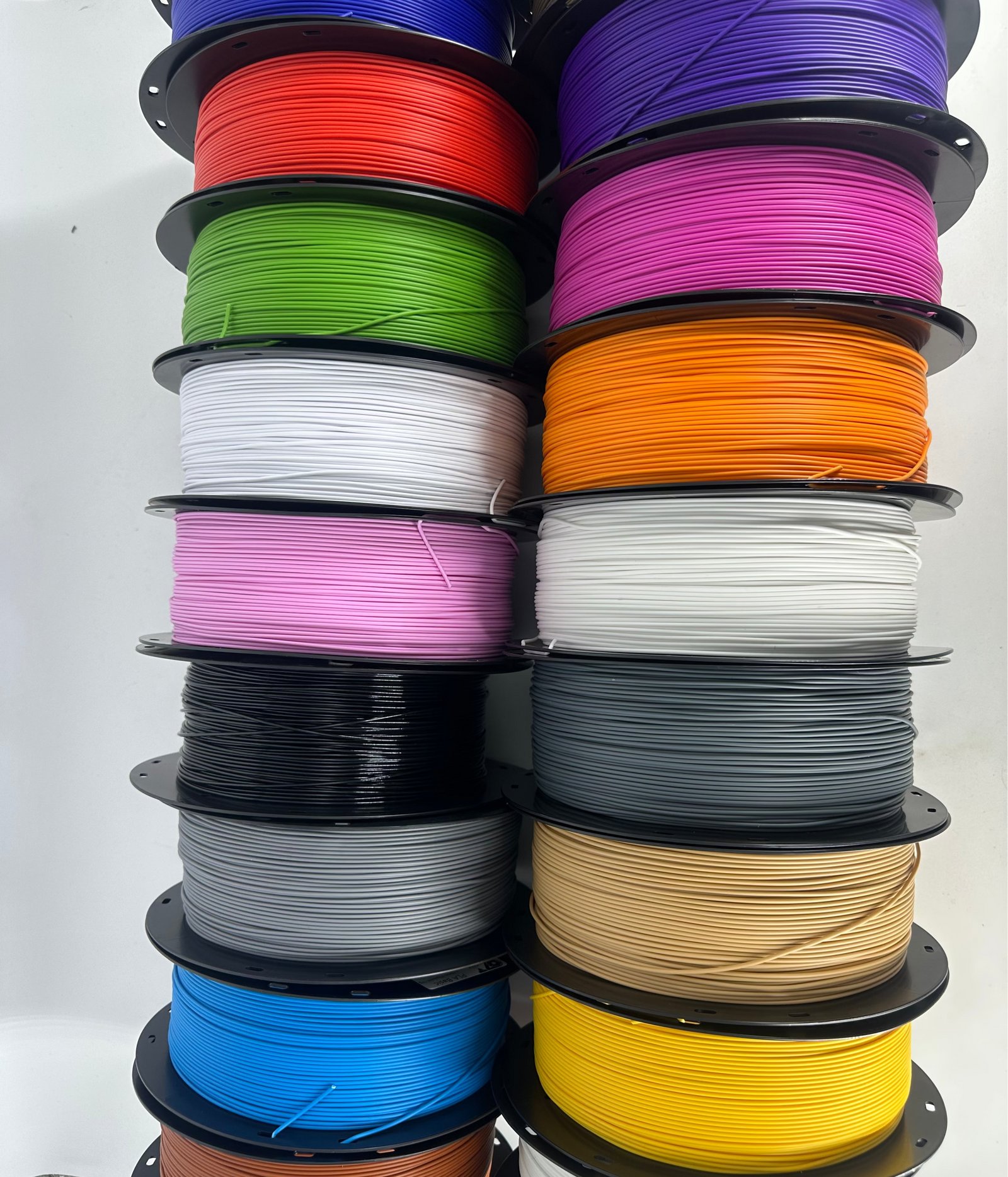 Shelf of OzFDM PLA Basic spools in purple, green, blue, grey, pink, white, orange and yellow