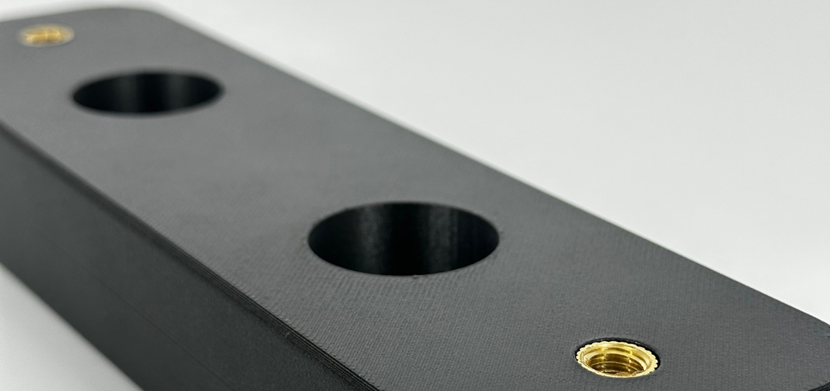 Brass threaded heat insert set into a black 3D printed bracket
